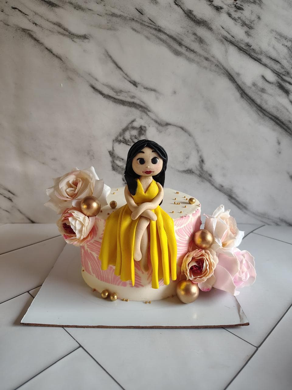 Yellow princess-themed cake with a figurine and sugar flowers