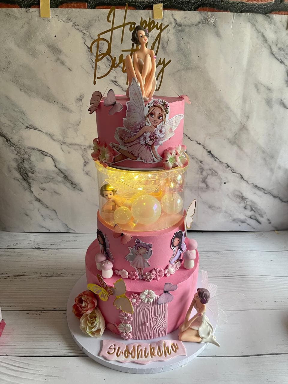 Pink three-tier fairy birthday cake with butterflies and floral details