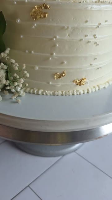 Close-up of white cake frosting with pearl piping and gold leaf