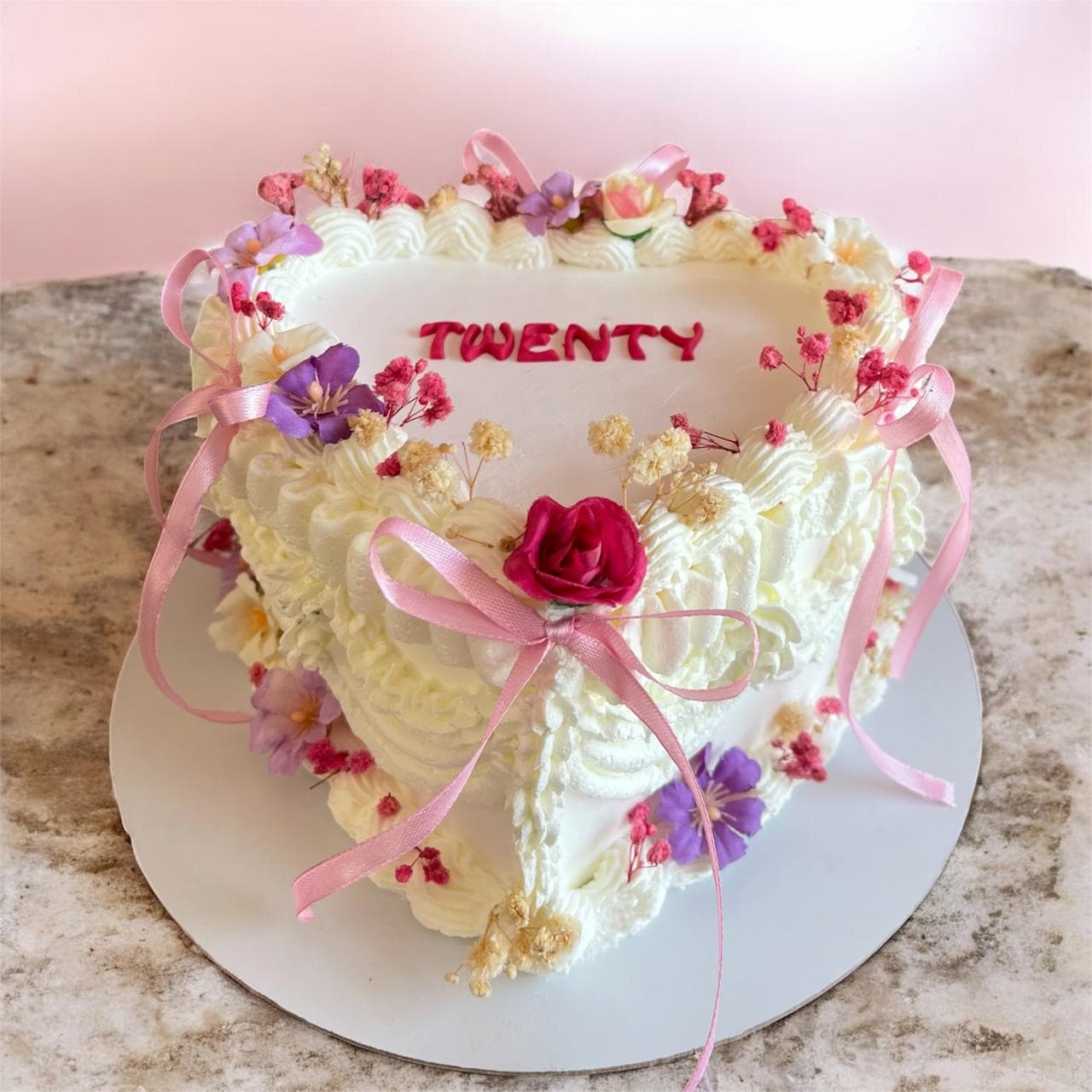 White twentieth birthday cake with pastel flowers and ribbon details