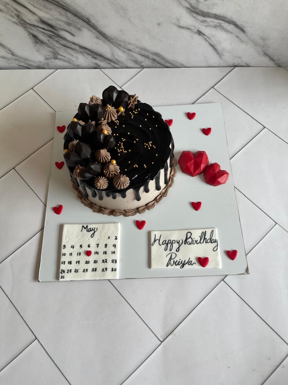 Chocolate drip birthday cake with heart decorations and a calendar plaque